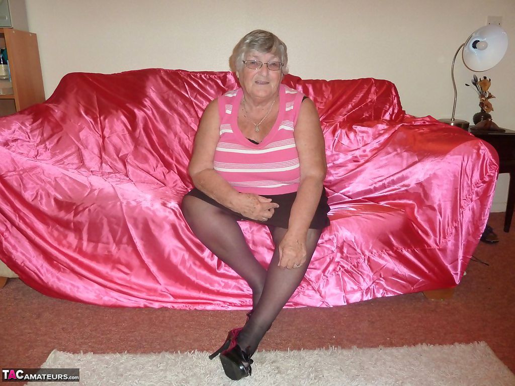 Obsese grandmother holds her fat rolls while stripping to black stockings