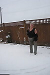Naughty granny Girdle Goddess strips to her stockings and boots while it snows