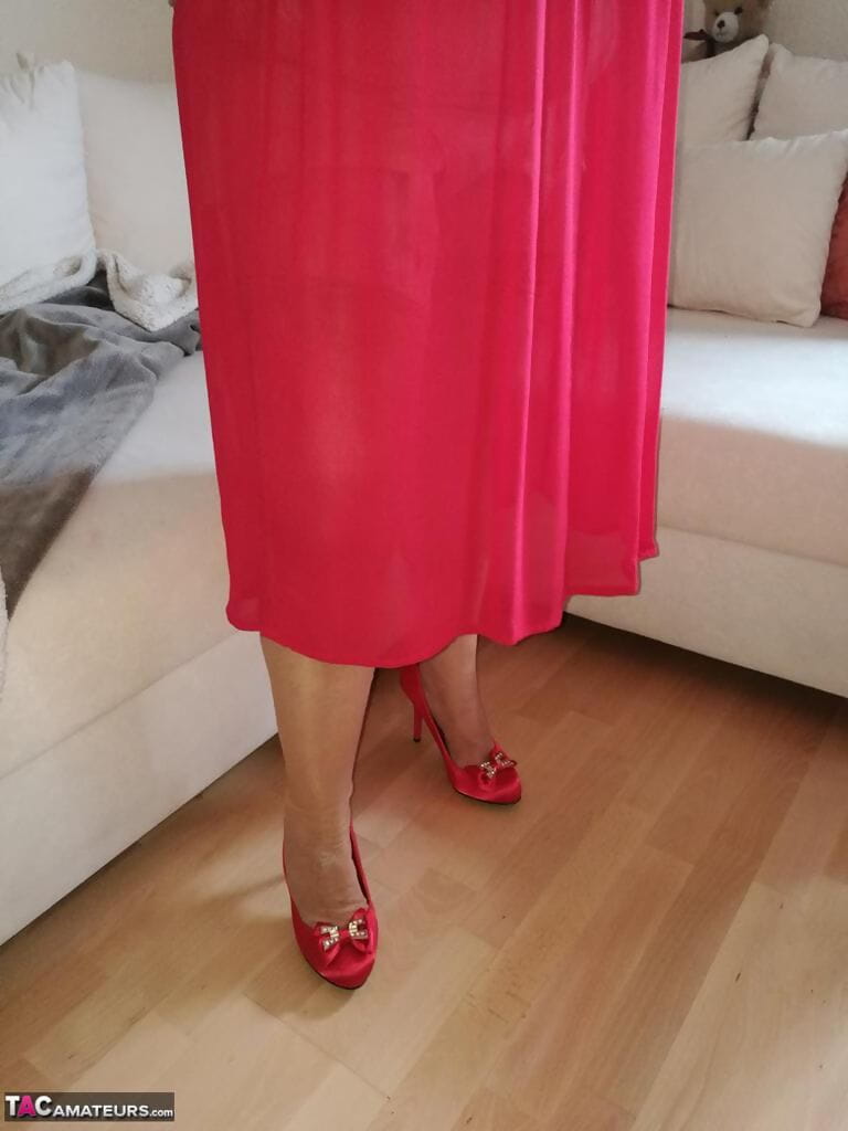 Horny oma Caro hikes up long red dress to spread her hairy vagina